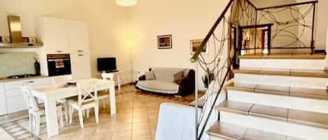 A spacious living area with a dining table, sofa, and staircase leading to an upper level.