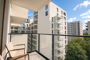A modern apartment with a balcony, large windows, and a view of other buildings. - Chmielna Duo Luxury | Warsaw Center & Parking (Warszawa)
