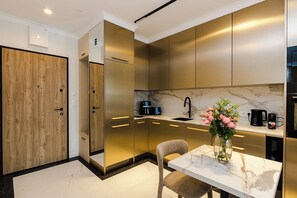 A modern kitchen with a marble countertop, a built-in oven, and a coffee maker. - Chmielna Duo Luxury | Warsaw Center & Parking (Warszawa)