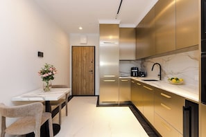 A modern kitchen with a marble countertop, a coffee maker, and a bowl of fruit. - Chmielna Duo Luxury | Warsaw Center & Parking (Warszawa)