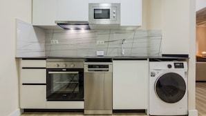 Cozinha compacta equipada com forno embutido, micro-ondas, máquina de lavar louça e máquina de lavar roupa.