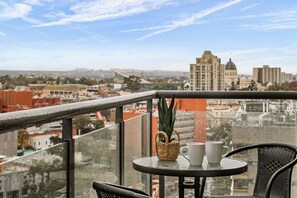 Ein Balkon mit Tisch, Stühlen, einer Topfpflanze und Blick auf eine Stadtansicht.