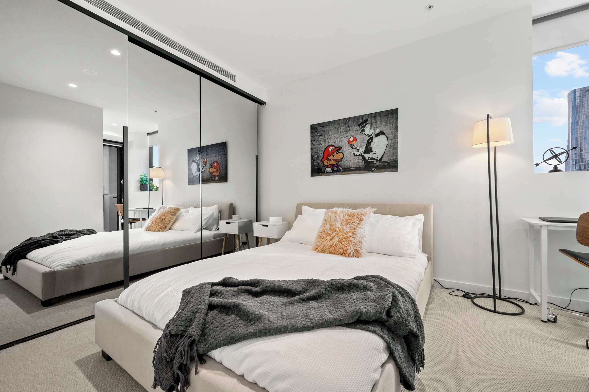 Una habitación de hotel moderna con una cama grande, una zona de estar, un escritorio y un espejo amplio.