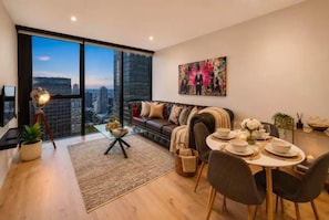 A modern living room with a dining area, large windows, and a city view. - City Centre on Best Street, Gym, WI-FI, Parking (Melbourne)