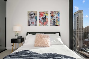 A modern bedroom with a bed, a nightstand, a lamp, and three wall art pieces. - City Centre on Best Street, Gym, WI-FI, Parking (Melbourne)