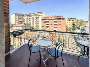 A balcony with a table and two chairs, overlooking a residential area with multi-story buildings. - Civico 9 (Mestre)