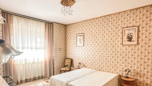 Une chambre à coucher avec un lit, une chaise, une table de chevet, une lampe et un papier peint à motifs.