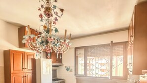 Une cuisine avec un sol carrelé, des meubles en bois, un réfrigérateur, une cuisinière et une fenêtre donnant sur un beau paysage.