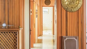 A wooden hallway with a clock, a patterned wall, and a door leading to another room. - Civico 9 (Mestre)