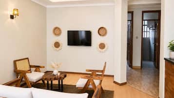 A living room with a sofa, chairs, a coffee table, a flat-screen TV, and decorative wall art.