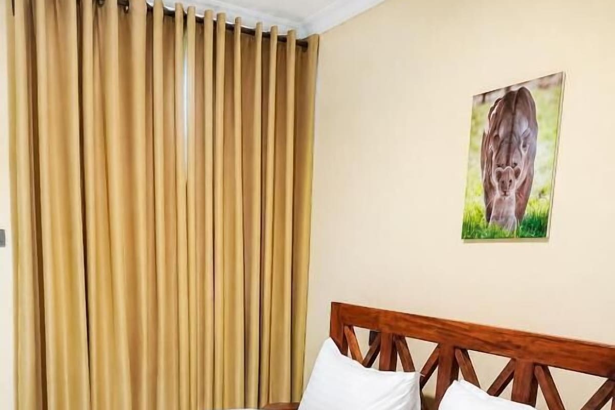 Una habitación de hotel con cama, cortinas y un cuadro en la pared.