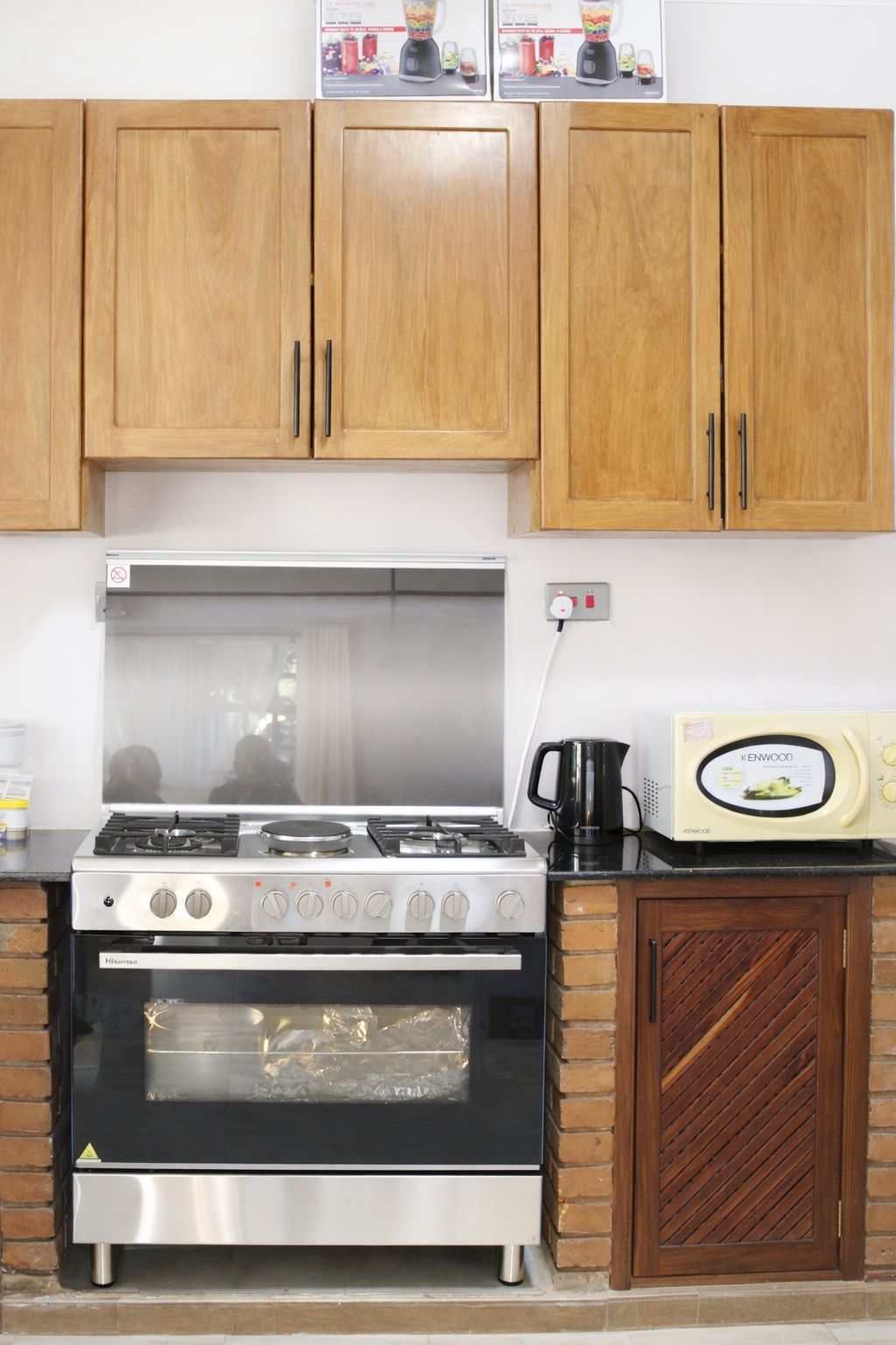 A kitchen with wooden cabinets, a gas stove, an oven, and a microwave.