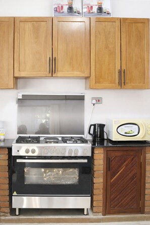 Una cocina con gabinetes de madera, estufa a gas, horno y microondas.