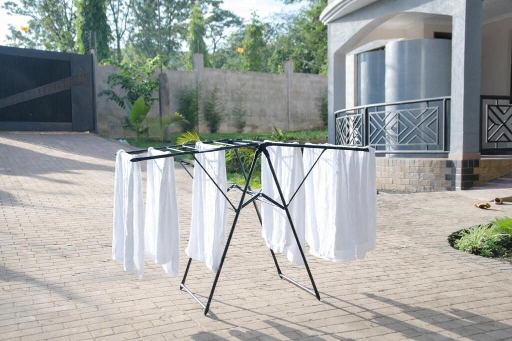 A metal drying rack with white garments in an outdoor setting.