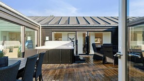 Eine moderne Außenpatio mit Whirlpool, Korbmöbeln und einer Holzterrasse.