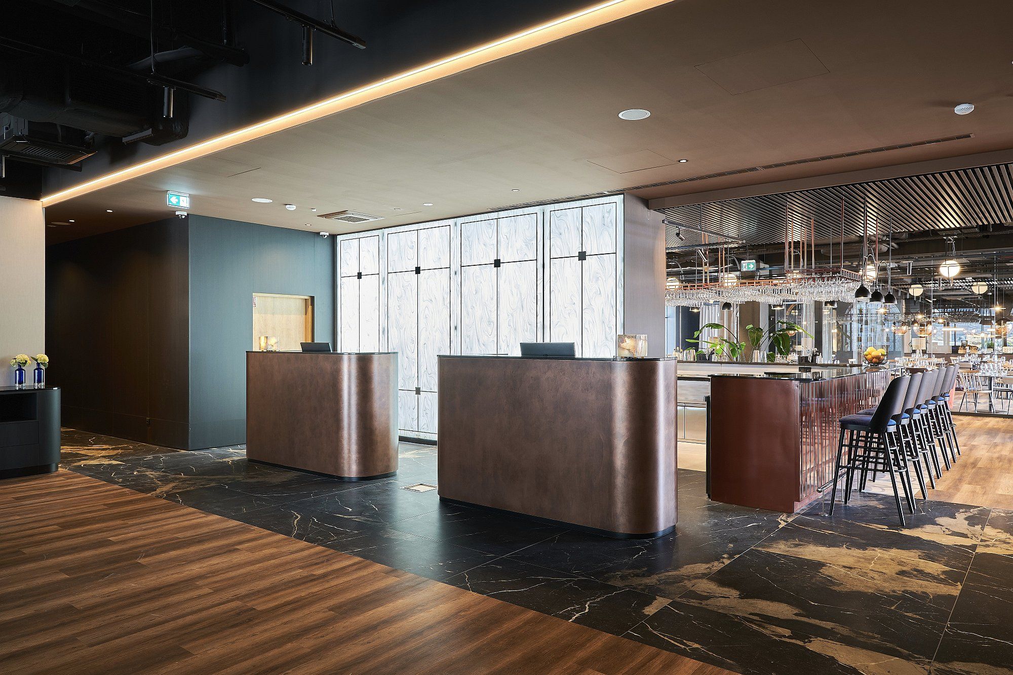 A modern reception area with a marble floor, two reception desks, and a bar area with seating.