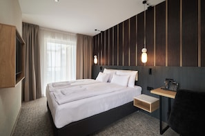 A hotel room with a large bed, bedside table, and a desk with a phone. - Harmony Valley Resort (Szklarska Poreba)