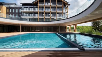 Ein modernes Hotel mit Schwimmbad, mehreren Balkonen und einer gebogenen Glasfassade.