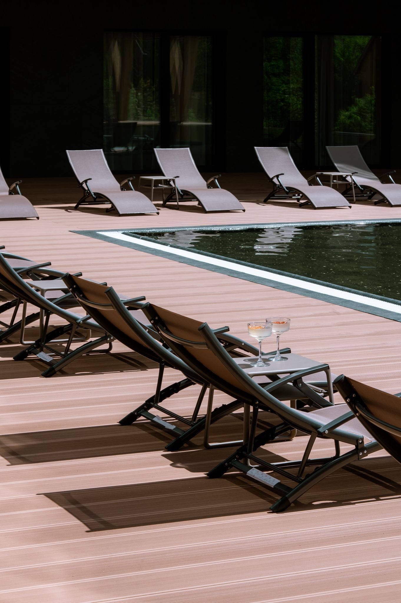 A poolside area with lounge chairs and a table with glasses.