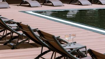 A poolside area with lounge chairs and a table with glasses.