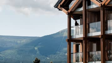 Un edificio de varios pisos con fachada de madera y grandes ventanales, con vistas a un paisaje montañoso.