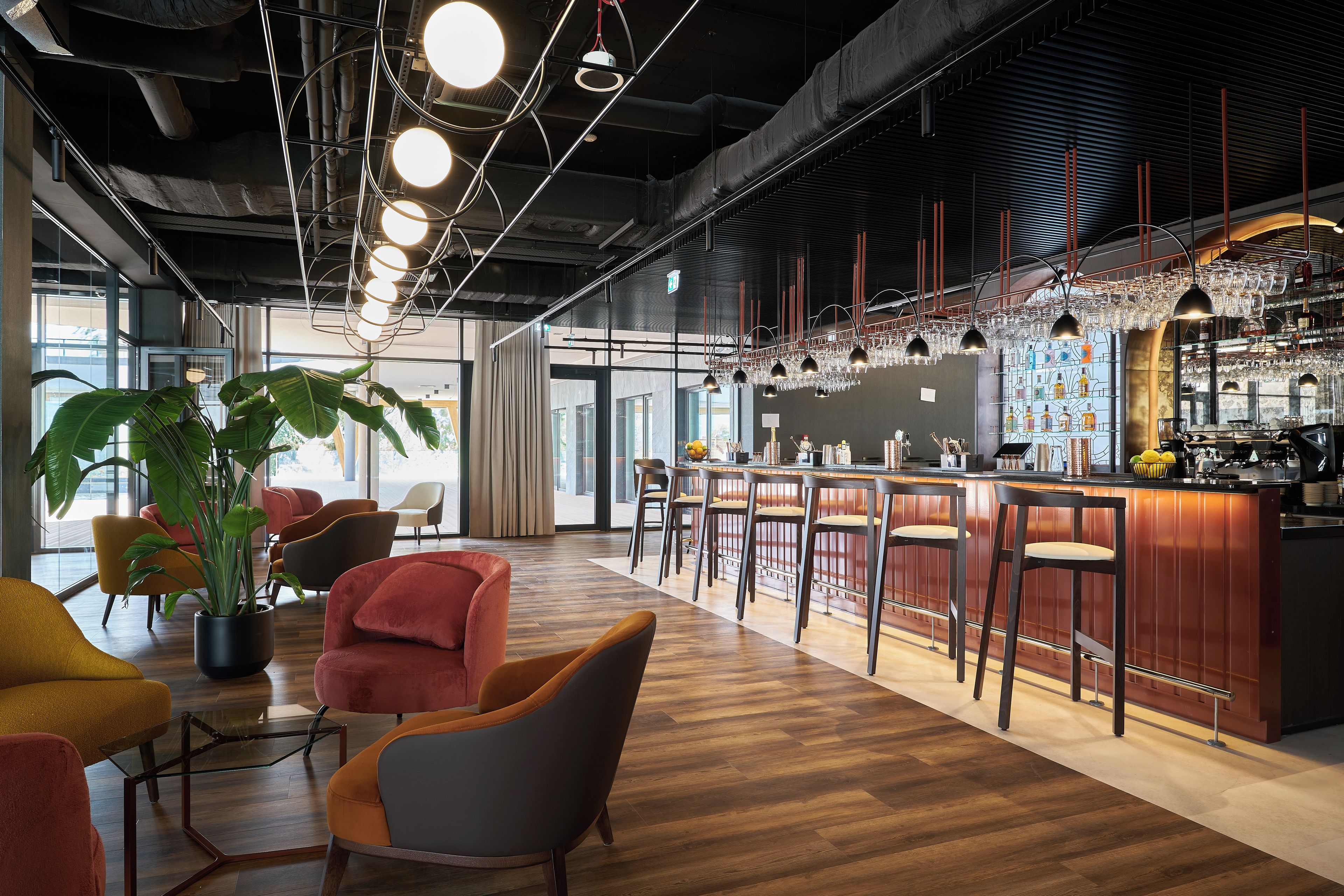 Un espace bar moderne avec un plancher en bois, des tabourets de bar et une variété de verres.