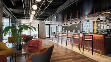 Un espace bar moderne avec un plancher en bois, des tabourets de bar et une variété de verres.