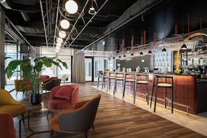 A modern bar area with a wooden floor, bar stools, and a variety of glassware.