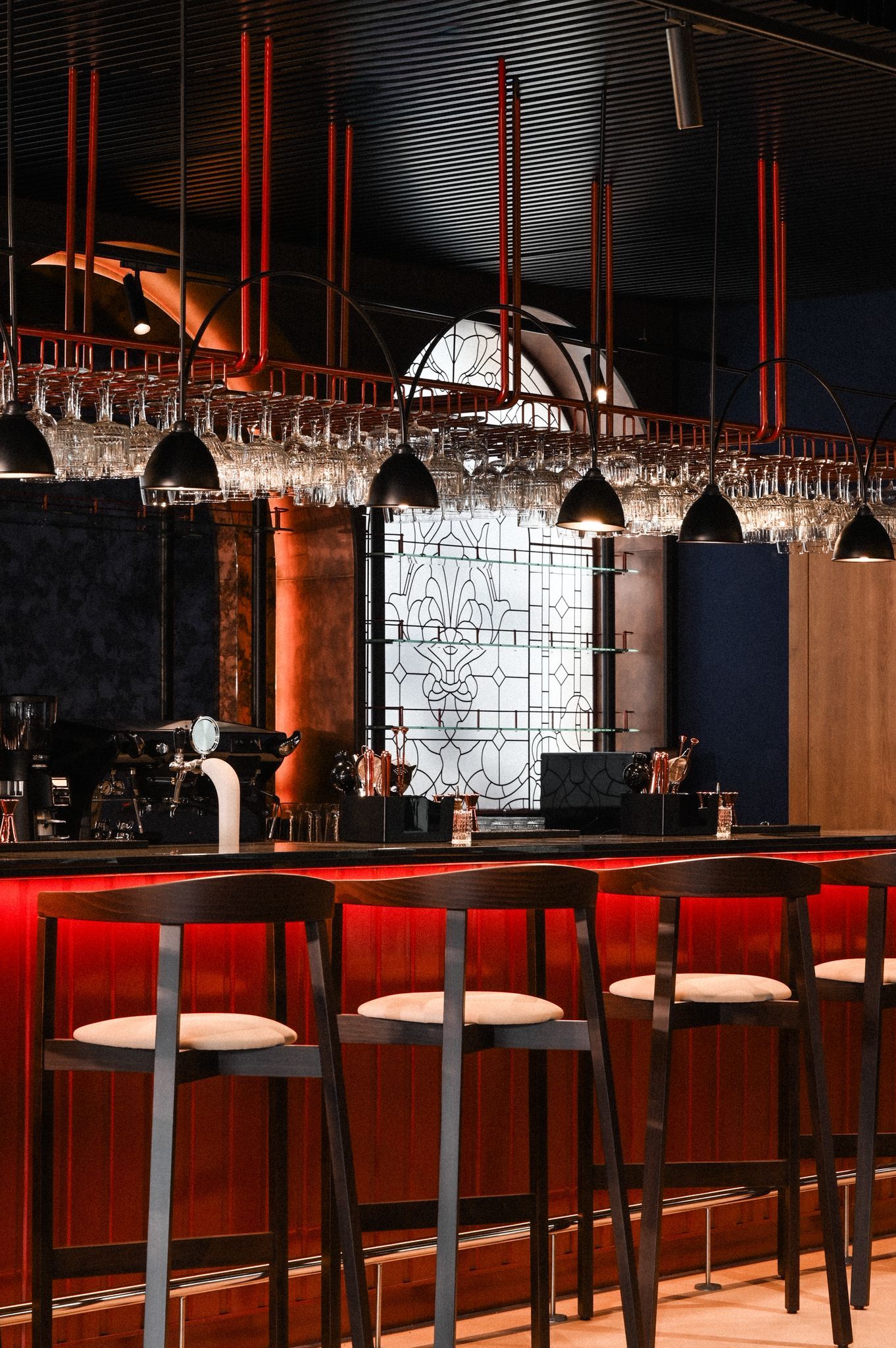 A bar area with multiple stools, a bar counter, and a decorative glass partition.