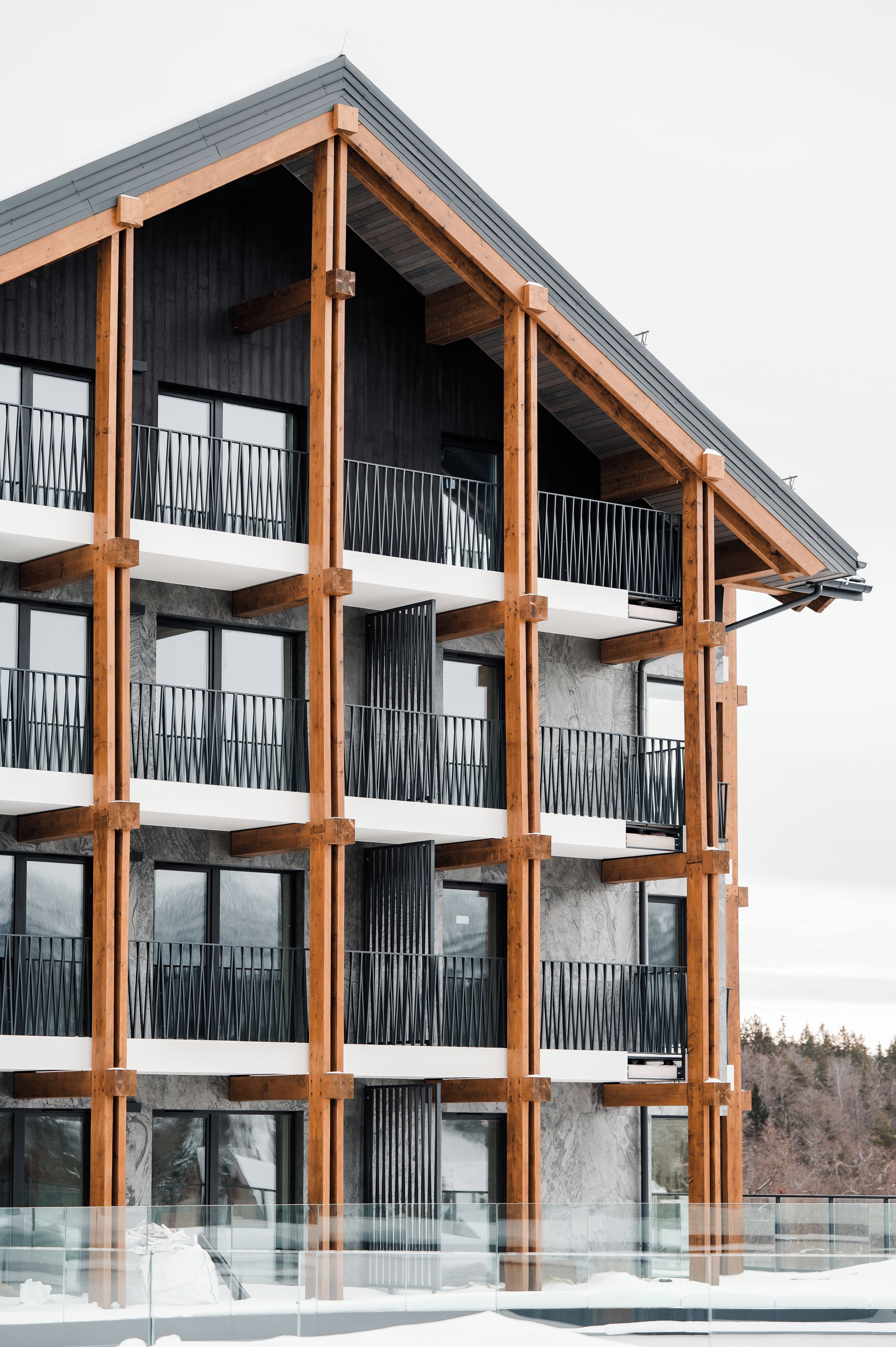 Un immeuble à plusieurs étages doté d’une architecture moderne, caractérisé par une série de balcons avec des garde-corps en métal et de grandes fenêtres.