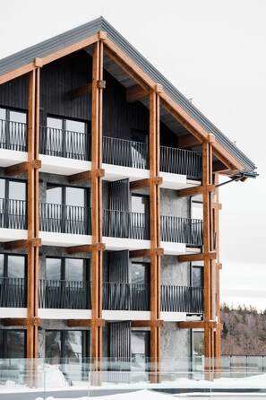 A multi-story building with a modern architectural design, featuring a series of balconies with metal railings and large windows. - Harmony Valley Resort (Szklarska Poreba)