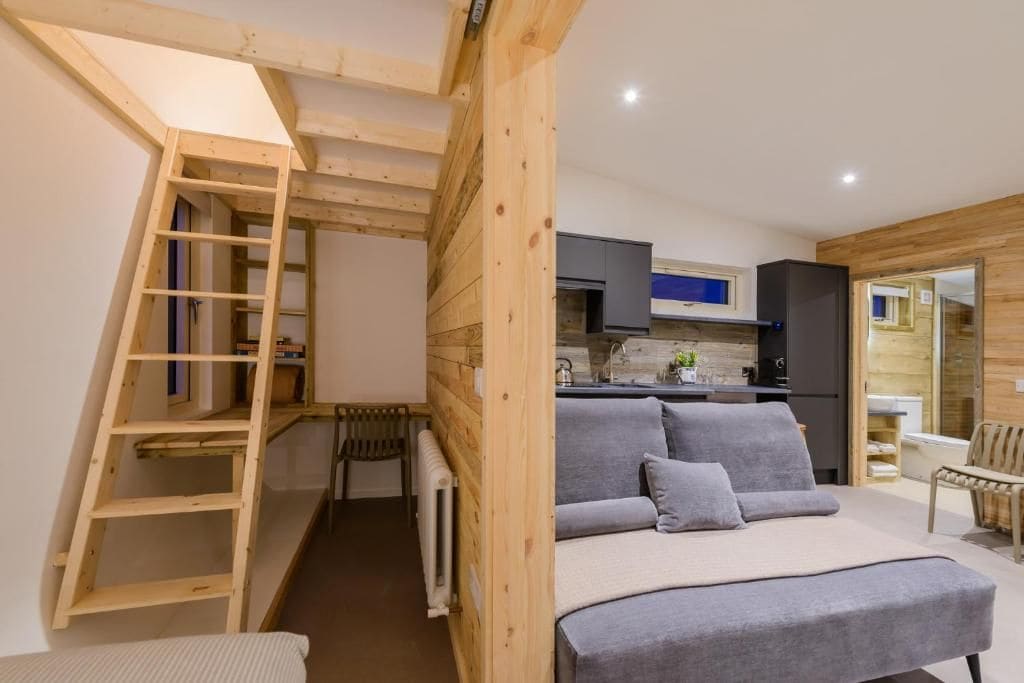 Habitación compacta con zona de descanso en entrepiso, kitchenette y armario empotrado.