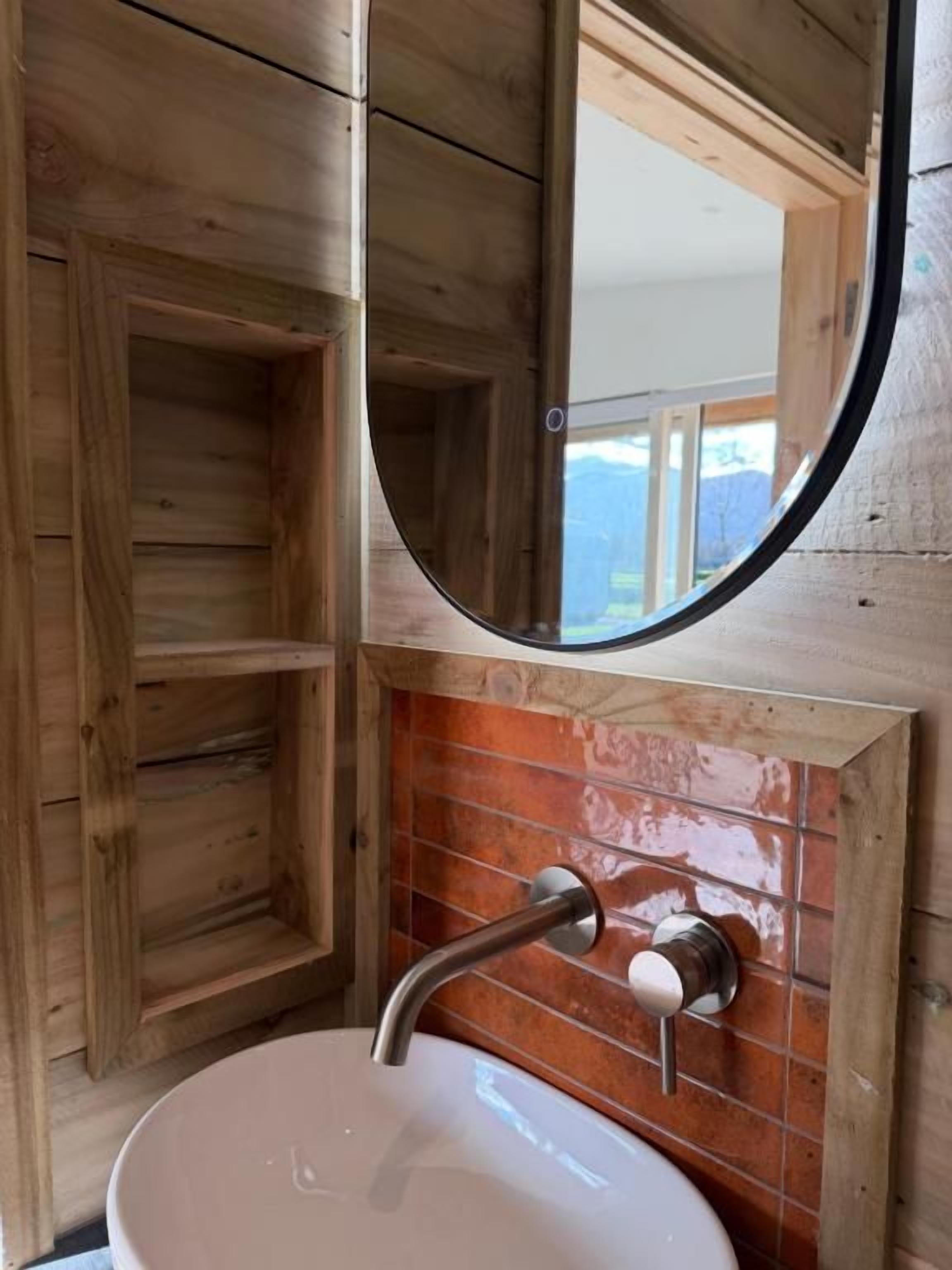A wooden interior with a round mirror above a white sink.