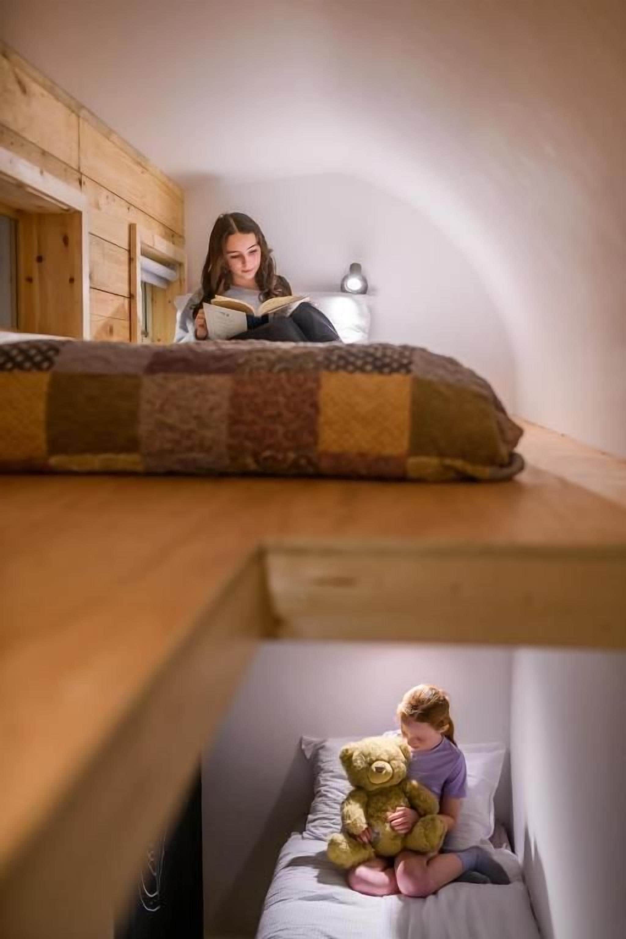 Una habitación con una cama litera y una cama inferior con un osito de peluche.