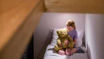 Una habitación con una cama litera y una cama inferior con un osito de peluche.