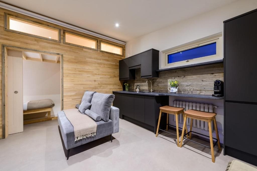 Un espacio habitable compacto con kitchenette, un sofá y un pequeño comedor.