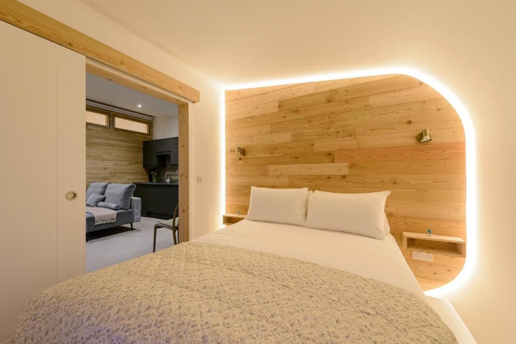 Un dormitorio con una cama, cabecera de madera y una mesita de noche.