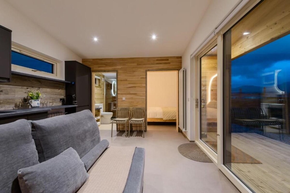 Ein modernes Interieur mit einer Couch, einem Essbereich und einer großen Schiebetür zu einem Außenbereich.