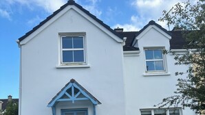 A two-story house with a blue door and windows. - Charming 4-bedroom House in Skibbereen - Pet Friendly Retreat (Skibbereen)