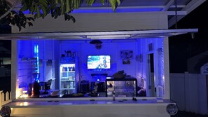 Eine Bar mit Fernseher, Regalen voller Flaschen und einer Sitzecke.