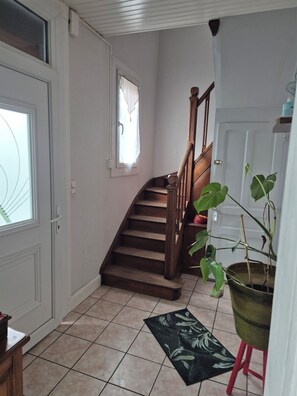 A staircase leading to a second floor, a potted plant, and a door with a window. - Large village house, 90 m² – Sleeps 10 – Lac du Der – 8 km from Saint-Dizier (Hallignicourt)