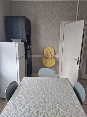 A room with a dining table, chairs, a refrigerator, a cabinet, and a door. - Large village house, 90 m² – Sleeps 10 – Lac du Der – 8 km from Saint-Dizier (Hallignicourt)