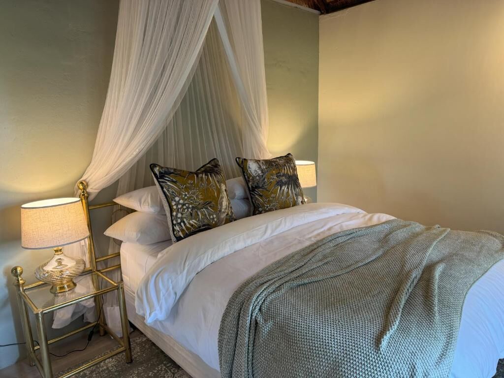 Una cama con dosel, dos lámparas de noche y almohadones decorativos.