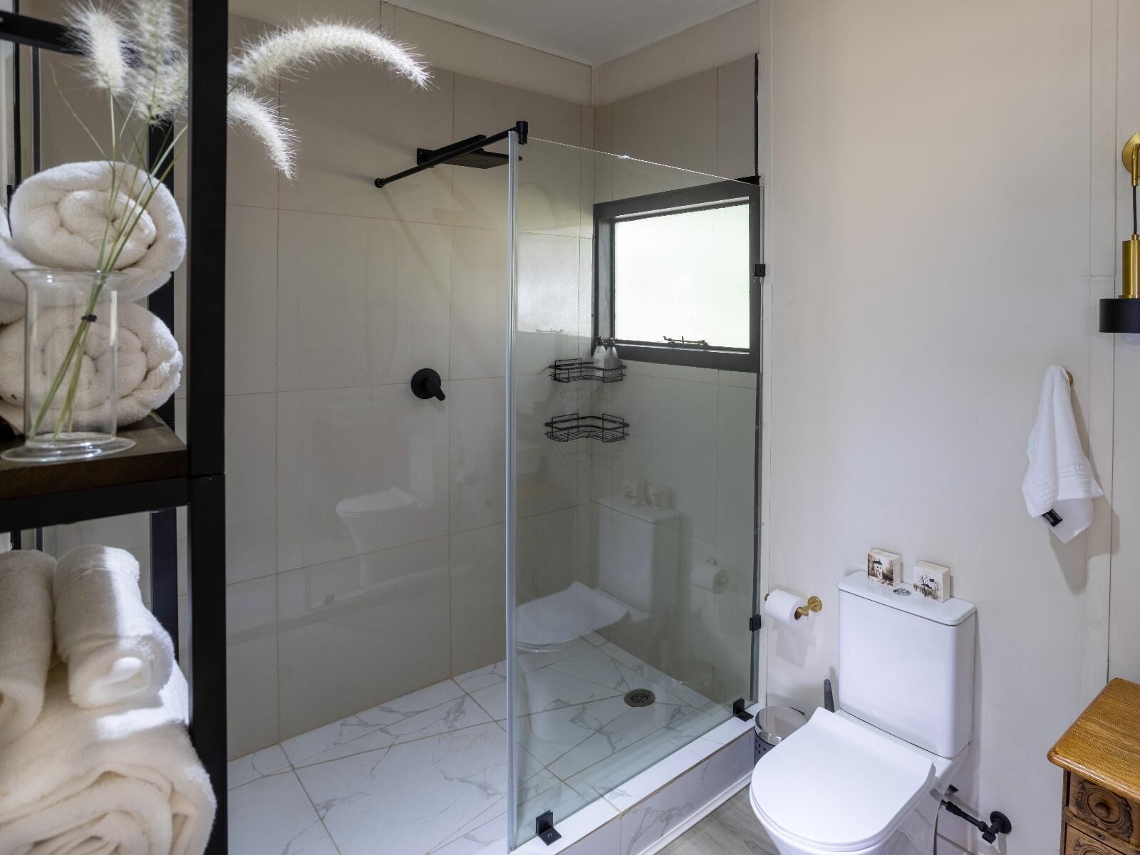 Ein modernes Badezimmer mit einer Duschkabine, einer Toilette und einem Handtuchhalter.