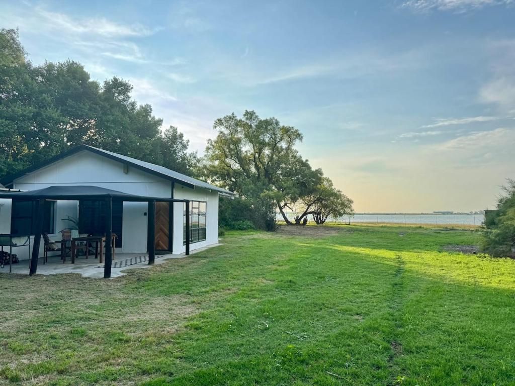Uma casa moderna com varanda coberta, gramado e vista para o mar.