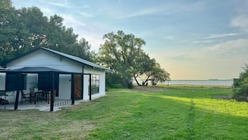 Uma casa moderna com varanda coberta, gramado e vista para o mar.
