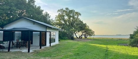 Una casa moderna con porche cubierto, césped y vista al mar.