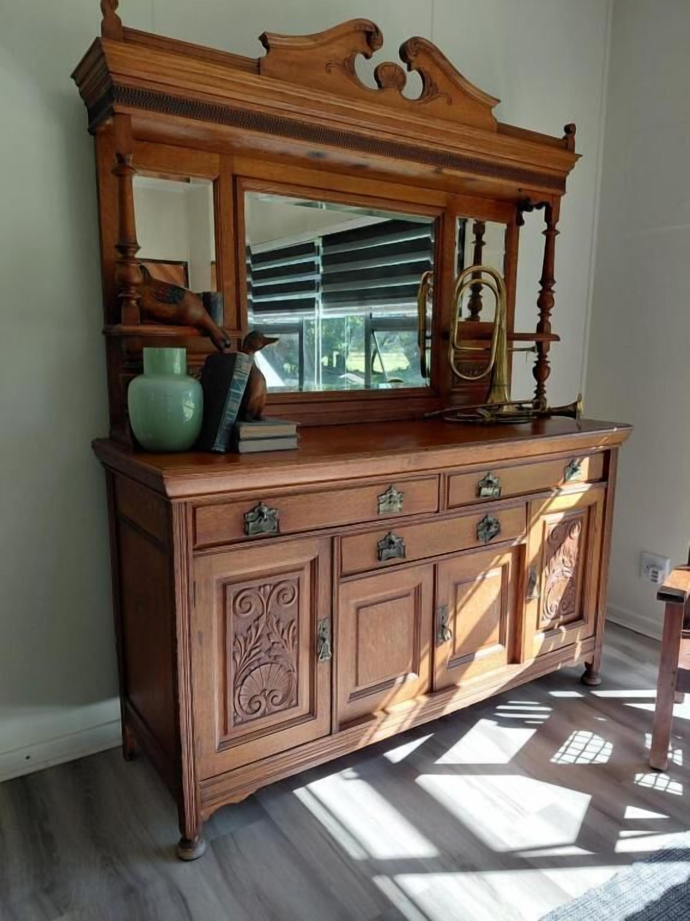 A wooden dresser with a mirror, drawers, and decorative elements.