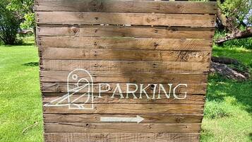 A wooden sign with a parking symbol and an arrow indicating the direction to the parking area.