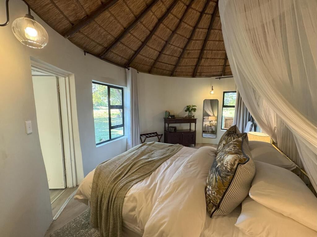 Un dormitorio con cama, espejo, mesita de noche y ventana.